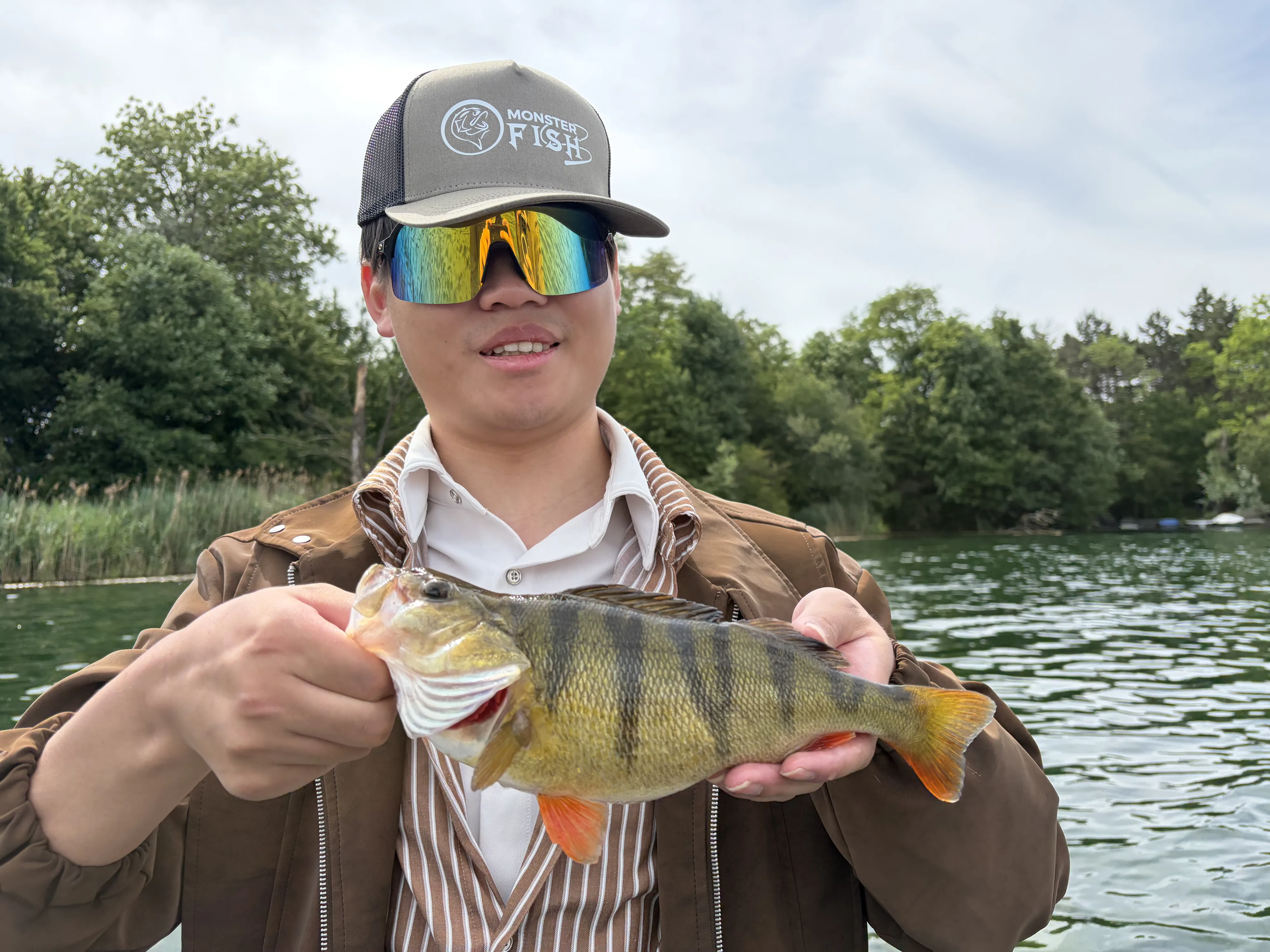 Angler mit einem prächtig gezeichneten Flussbarsch im Boot